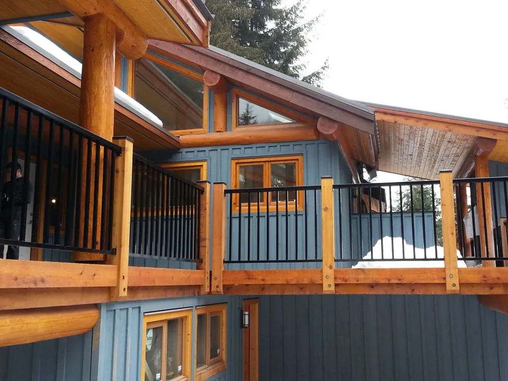 The wooden cabin exterior, enhanced by large log beams and black railings, exudes rustic charm. Its