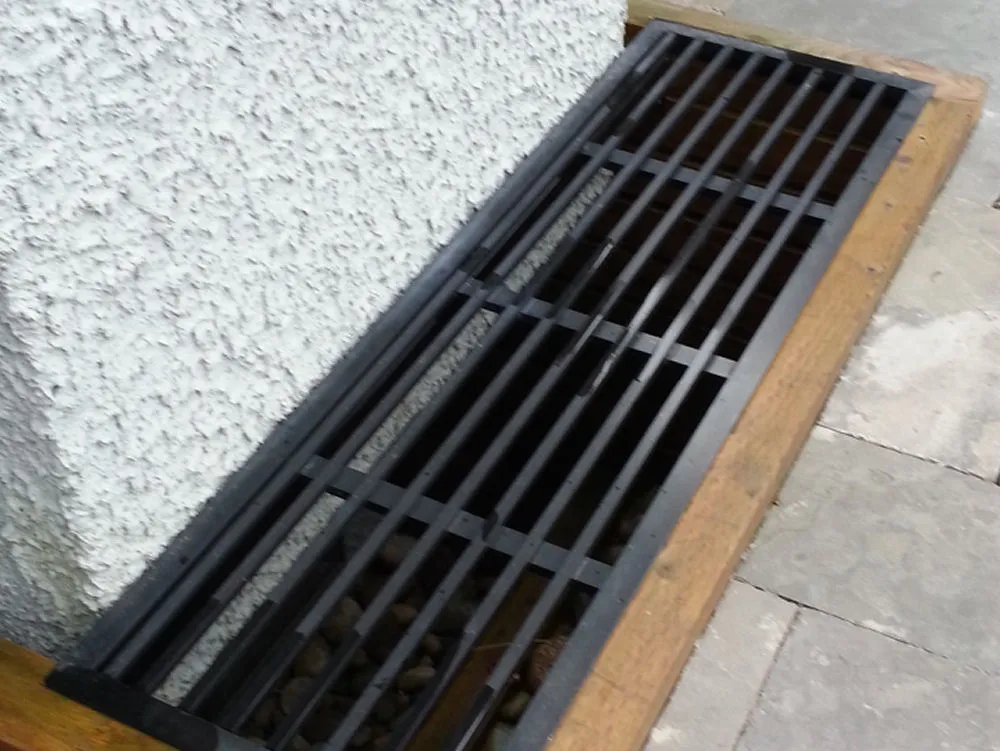 A product of fine craftsmanship, the metal grate elegantly covers a basement window well. It rests