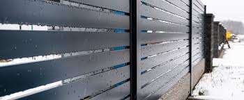 Close-up view of a modern horizontal metal slat fence outdoors, featuring sleek aluminum railings
