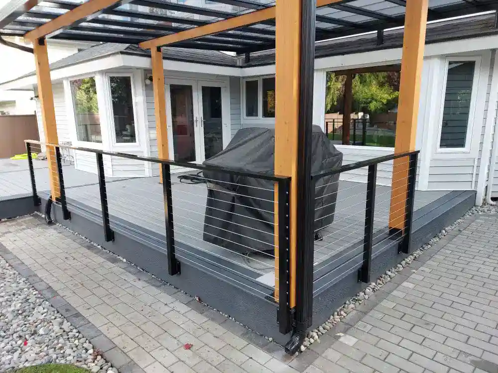 Modern backyard deck with a glass roof, custom aluminum railings, and a covered grill at the center