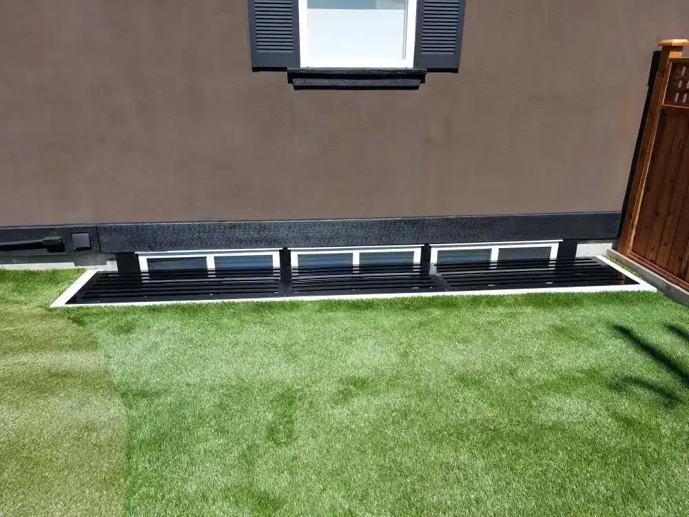 Four small horizontal windows at the base of a brown building, protected by sturdy black window